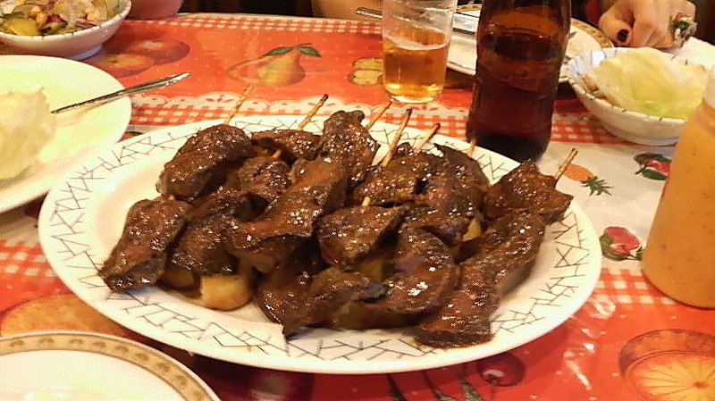 Anticucho (roasted cow heart on skewers) on a bed of potato.