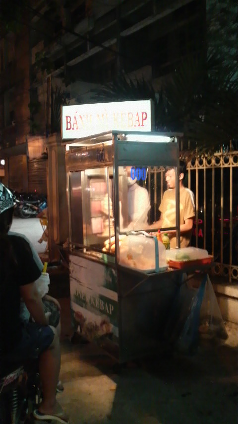 Two smiling staff work a kebab stand in central Sai Gon on a humid Monday night