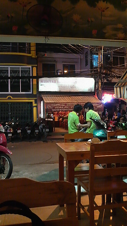 Mumtaz seen from across the road, inside the Coriander Thai restaurant. The Coriander staff are wearing green shirts; the Mumtaz staff wear some kind of yellow/orange outfit, if I recall correctly.